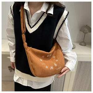 Detalle de bolso bandolera de pana marrón con bordado blanco circular de estilo retro