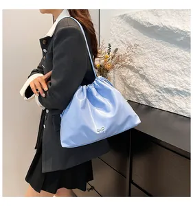 Vue latérale du sac plissé bleu clair avec petit nœud argenté porté à l'épaule