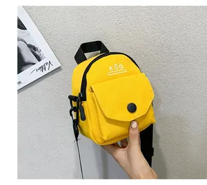 Close-up of yellow canvas mini crossbody bag with KǑQ logo and black strap details