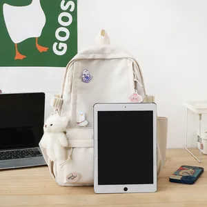Zaino minimalista in tela beige con spille e ciondolo a orsetto per studentesse