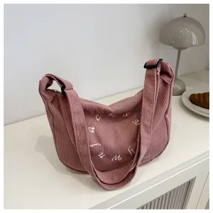 Detail of pink corduroy shoulder bag showing fine letter embroidery and texture