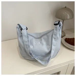 Detailed close-up of light blue corduroy tote bag featuring white embroidered letters