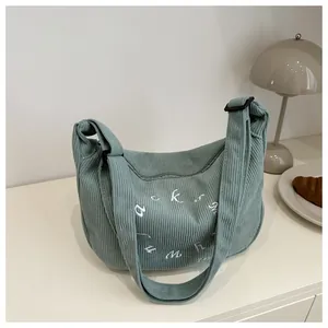 Detailed close-up of light green corduroy crossbody bag with white circular embroidery