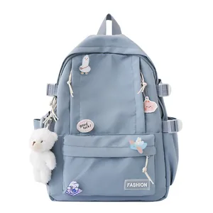 Zaino scolastico azzurro con simpatiche spille a cartone e un ciondolo a orsetto bianco