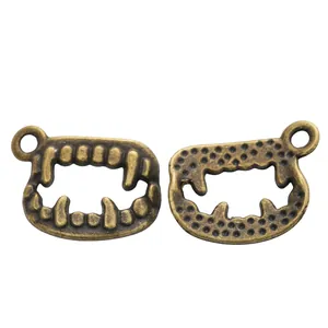 Pair of vintage bronze alloy vampire fang pendants showing front and textured back details