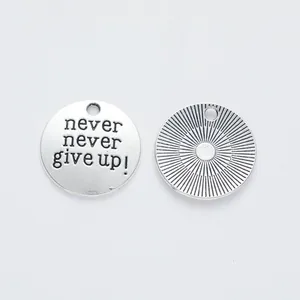 Detailed macro view of vintage silver alloy charms showing 'never give up' engraving and texture
