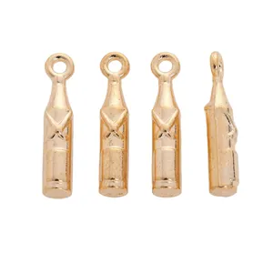 Detailed view of four golden bottle-shaped vintage alloy charms with embossed X design
