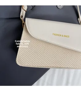 Detail van de crossbodytas met geweven textuur en glad kunstleer met gouden tekst