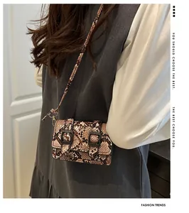 Détail de la texture serpent et boucle en métal sur le petit sac bandoulière marron
