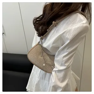 Détail du sac hobo doré pailleté avec breloques en perles et chaîne en cœur