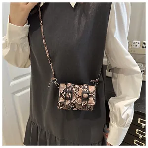 Détail d'un mini sac bandoulière à motif serpent avec boucles décoratives sur un mannequin