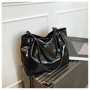 Détail d'un grand sac cabas en cuir verni noir avec boucle nœud argentée chic
