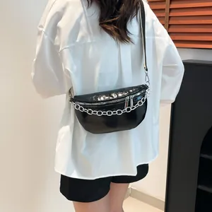 Fashionable black patent leather chest bag with silver chain worn by a model