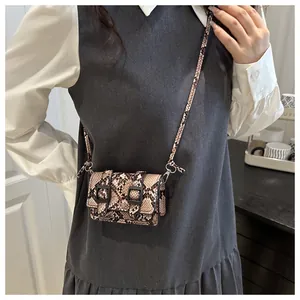Détail d'un mini sac bandoulière à motif serpent avec boucles noires et fine bandoulière