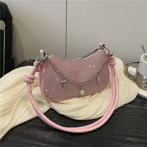 Sac hobo rose à paillettes avec bandoulière nouée et breloques cœur en décor lifestyle