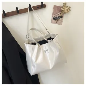 Détail d'un cabas blanc crème avec nœud métallique argenté et finition brillante