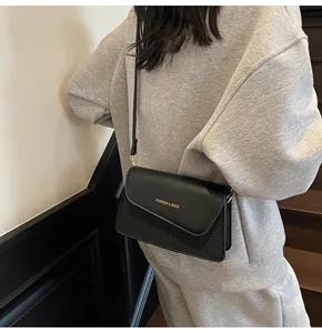 Detail of black crossbody bag with mixed textures and golden fashion lettering