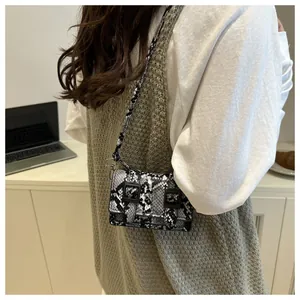 Détail du sac bandoulière motif serpent avec boucles noires et fine bandoulière