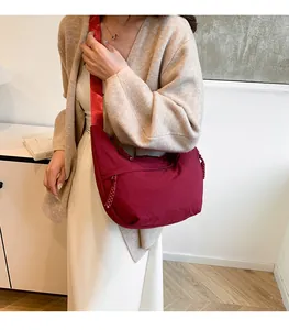 Détail du sac croissant en nylon bordeaux avec large bandoulière et texture plissée