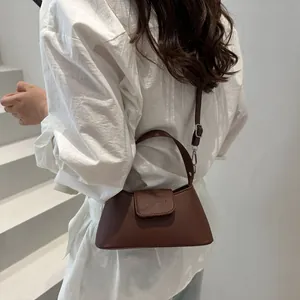 Mini sac à main en cuir marron avec bandoulière porté sur un modèle en chemise blanche