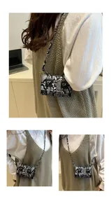 Détail du mini sac bandoulière motif serpent avec doubles boucles et longue bandoulière