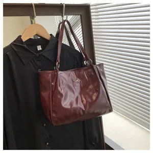 Détail d'un sac cabas rouge foncé avec ornement nœud argenté suspendu en intérieur
