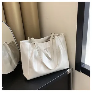 Détail du sac fourre-tout blanc crème en cuir brillant avec petit nœud métallique chic