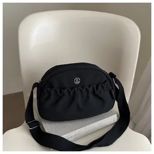 Minimalist black nylon crescent crossbody bag with adjustable strap and silver M logo