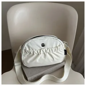 Creamy crescent nylon crossbody bag with pleated pockets and adjustable strap