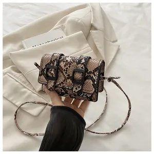 Détail de la texture serpent marron d'un sac bandoulière rétro avec doubles boucles