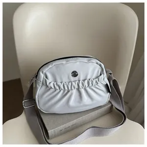 Beige nylon crossbody bag with pleated texture and adjustable wide shoulder strap