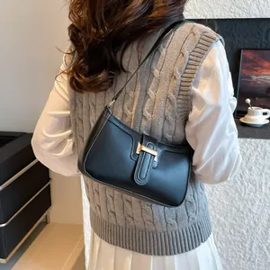 Classic black leather underarm bag with gold T-clasp shown on model in street style