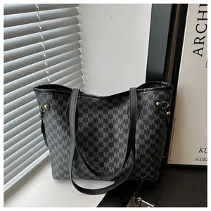 Detailed macro view of repeated grey M letter monogram print and gold hardware buckle on tote