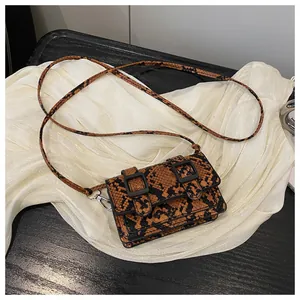 Détail du motif serpent orange sur petit sac à bandoulière avec doubles boucles noires