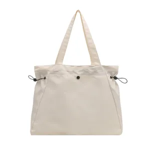 Minimalist cream nylon tote bag with black drawstring details and snap button closure