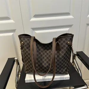 Brown monogram tote bag with double leather straps on a chair in a minimalist room setting