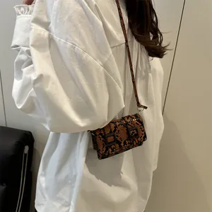 Sac bandoulière marron imprimé serpent avec boucles doubles sur chemise blanche
