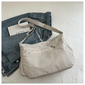 Detailed macro view of beige pleated messenger bag featuring wide adjustable strap and side pockets
