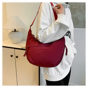 Détail du sac demi-lune en nylon bordeaux avec finition texturée et tirette de zip tressée