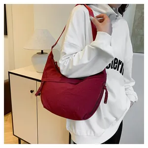 Detail showing the burgundy nylon crescent bag with braided zipper pulls and wide strap