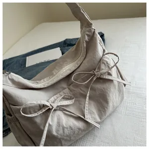 Close-up of pleated nylon messenger bag with ribbon bow details and side pocket