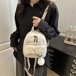 Japanse witte corduroy mini-rugzak met zwarte smileys gedragen door een model