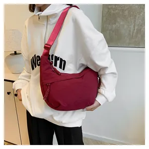 Burgundy nylon crescent crossbody bag featuring adjustable strap and woven zipper detail