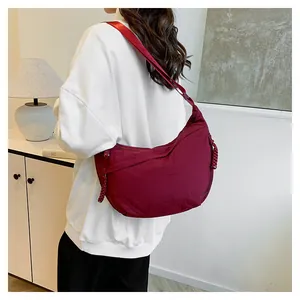 Detail view of the wine red nylon crescent crossbody bag with adjustable wide shoulder strap