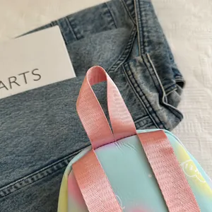Top view detail of a gradient pastel mini backpack with pink nylon handles and cloud pattern