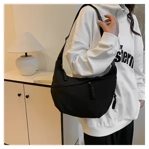 Détail du sac croissant en nylon noir avec tirette de zip tressée et bandoulière réglable