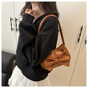 Close-up of brown PU leather shoulder bag featuring a large decorative bow and zipper