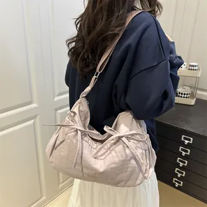 Detail of light purple pleated messenger bag featuring side bows and adjustable strap
