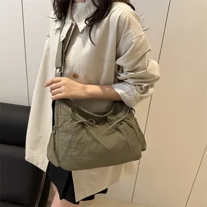 Detail of army green messenger bag featuring side drawstring pockets and wide strap