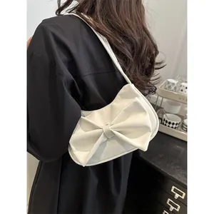 Minimalist white Y2K shoulder bag with large 3D butterfly bow in a soft side-view shot